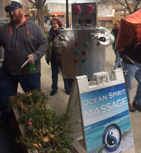 A man standing next to a sign that says " ocean spirit massage ".